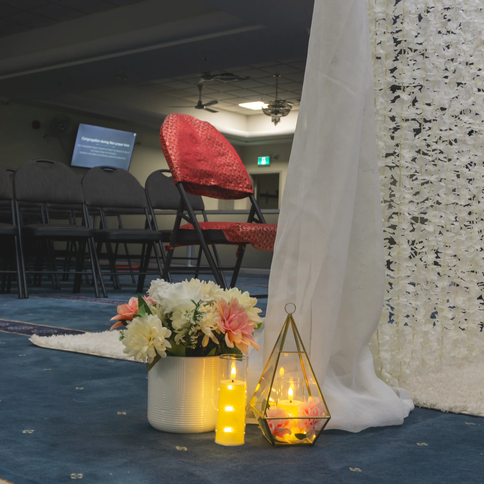 A floral arrangement and LED candles at the base of the flower wall
